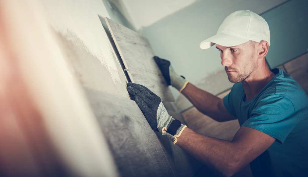 A man laying tiles on a wall