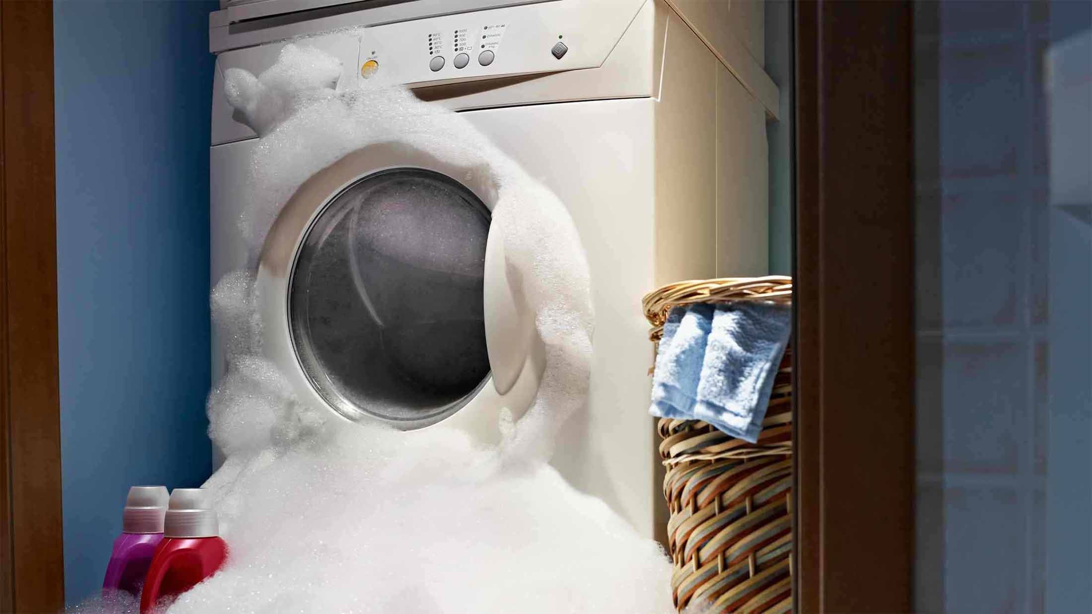 Faulty washing machine with soap suds spilling through the door