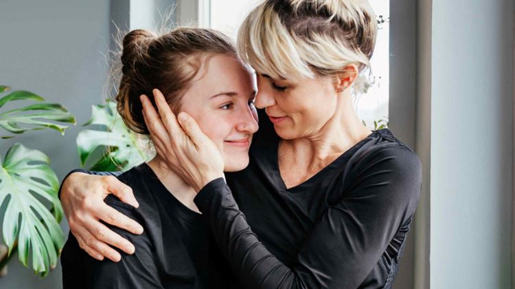 Mother hugging her daughter with her hand placed on the side of her face