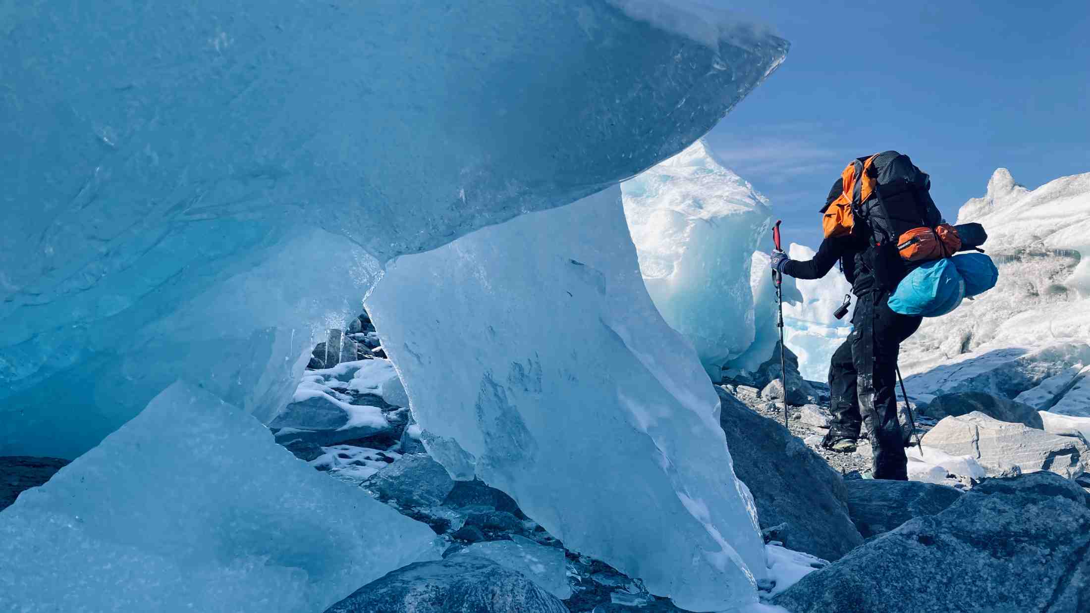 Cat Burford is climbing across an ice field and passing by a giant ice formation