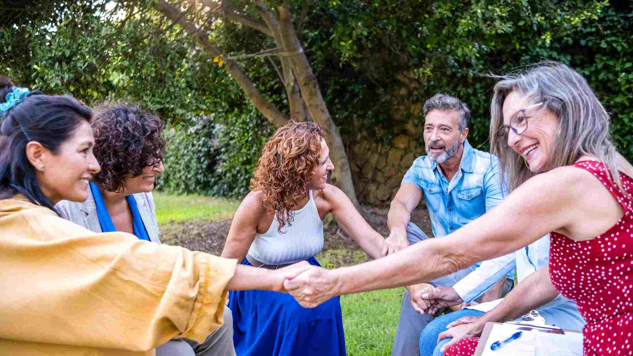 multi-ethnic group of people sitting outside talking and sharing their feelings with one another.