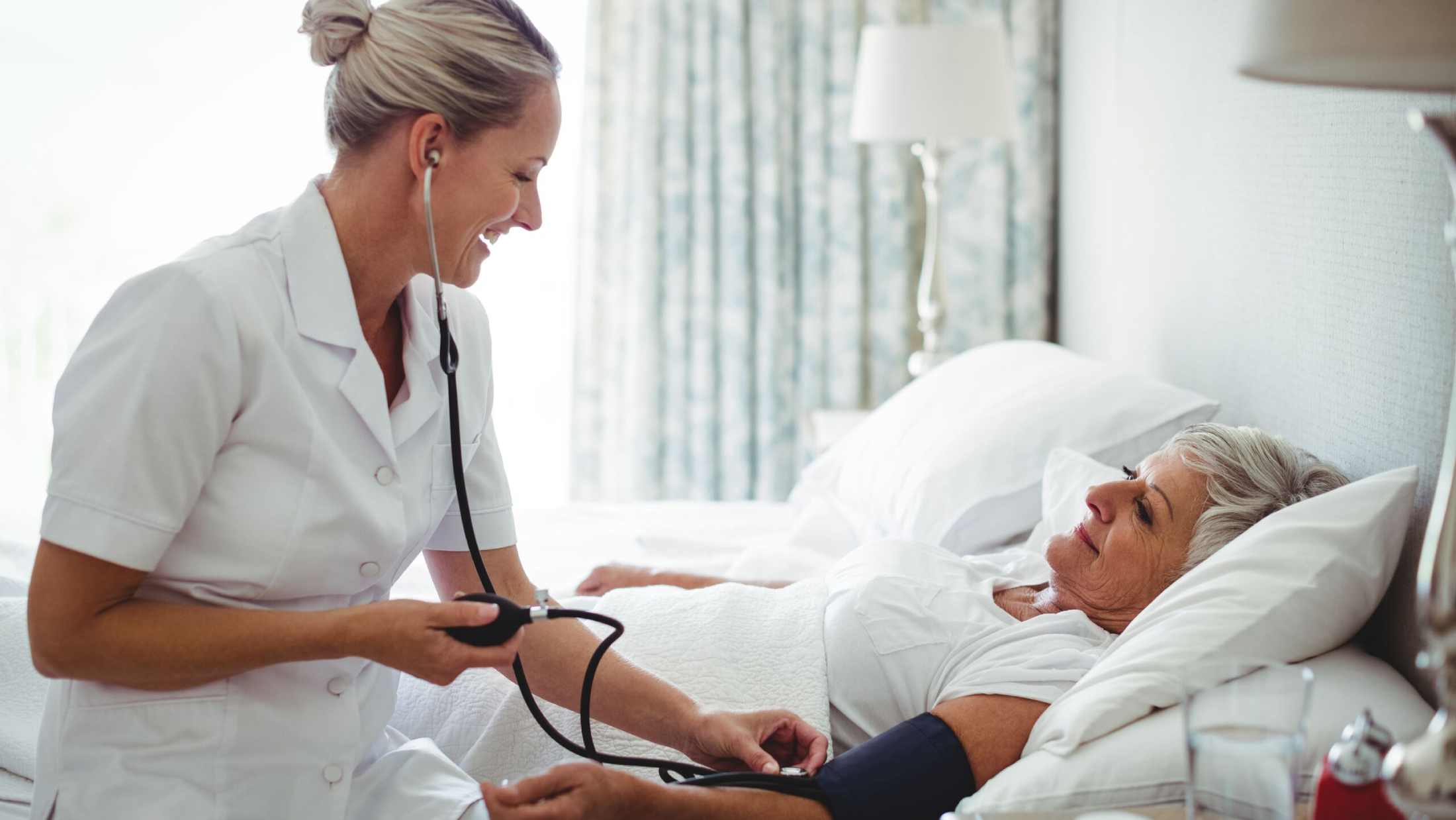 Nurse checking blood pressure of woman at home