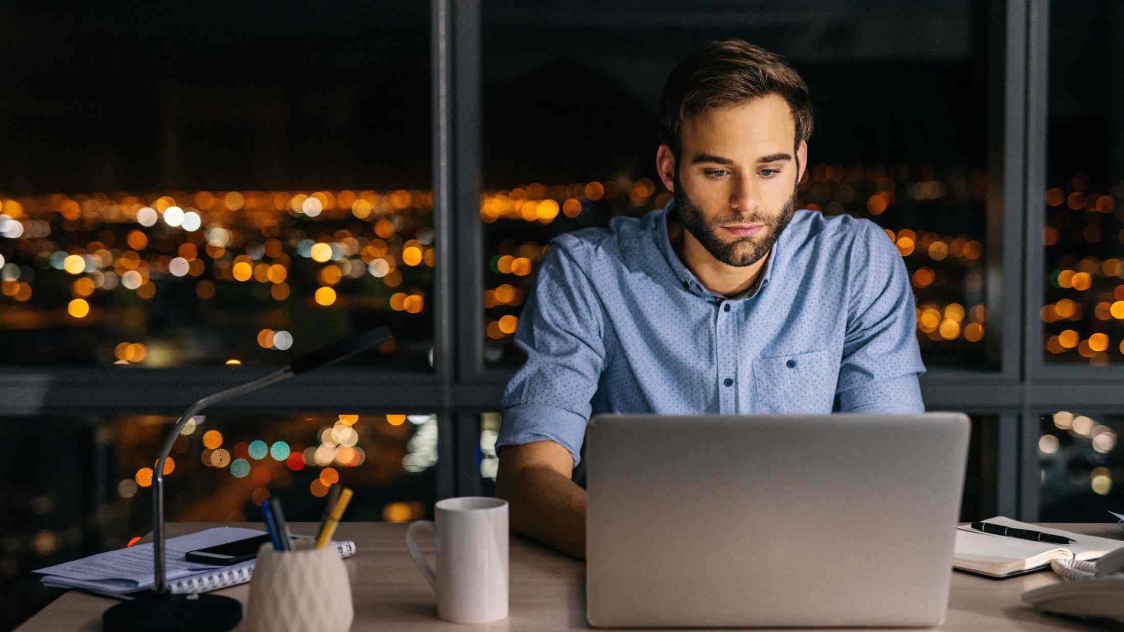 Young businessman working on a laptop at his office desk late into the night