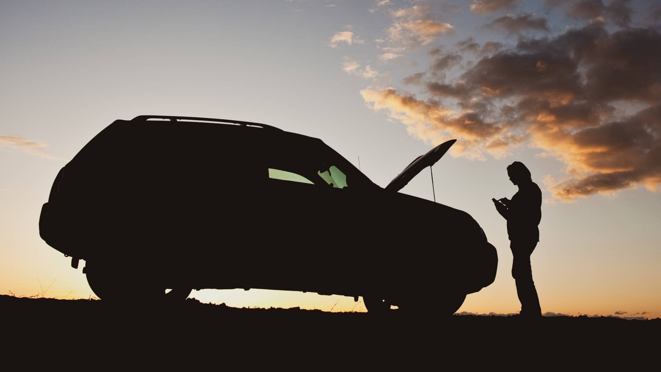 Woman texting for help with car trouble beside road