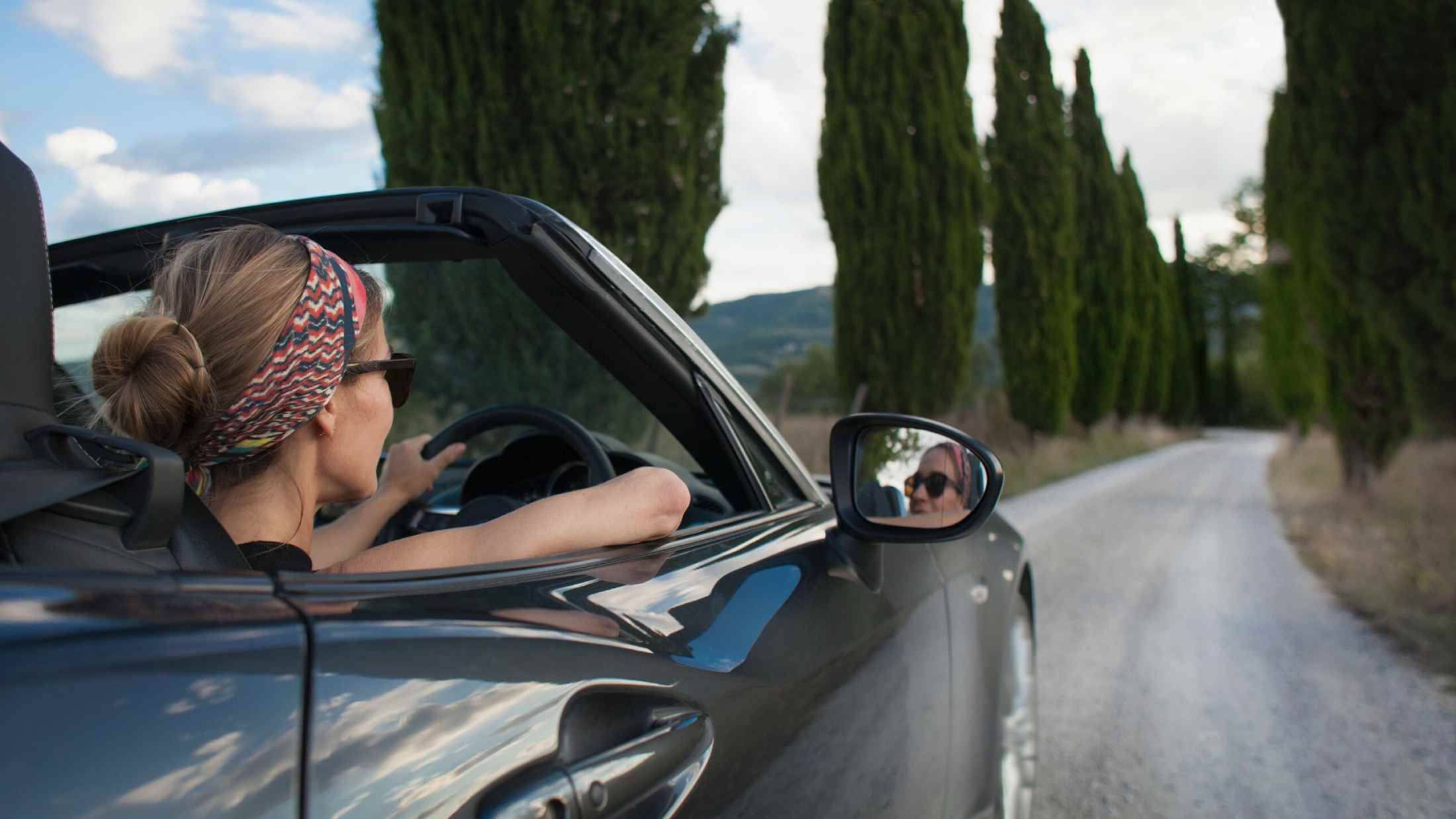 Woman driving convertible car on Tuscan country road