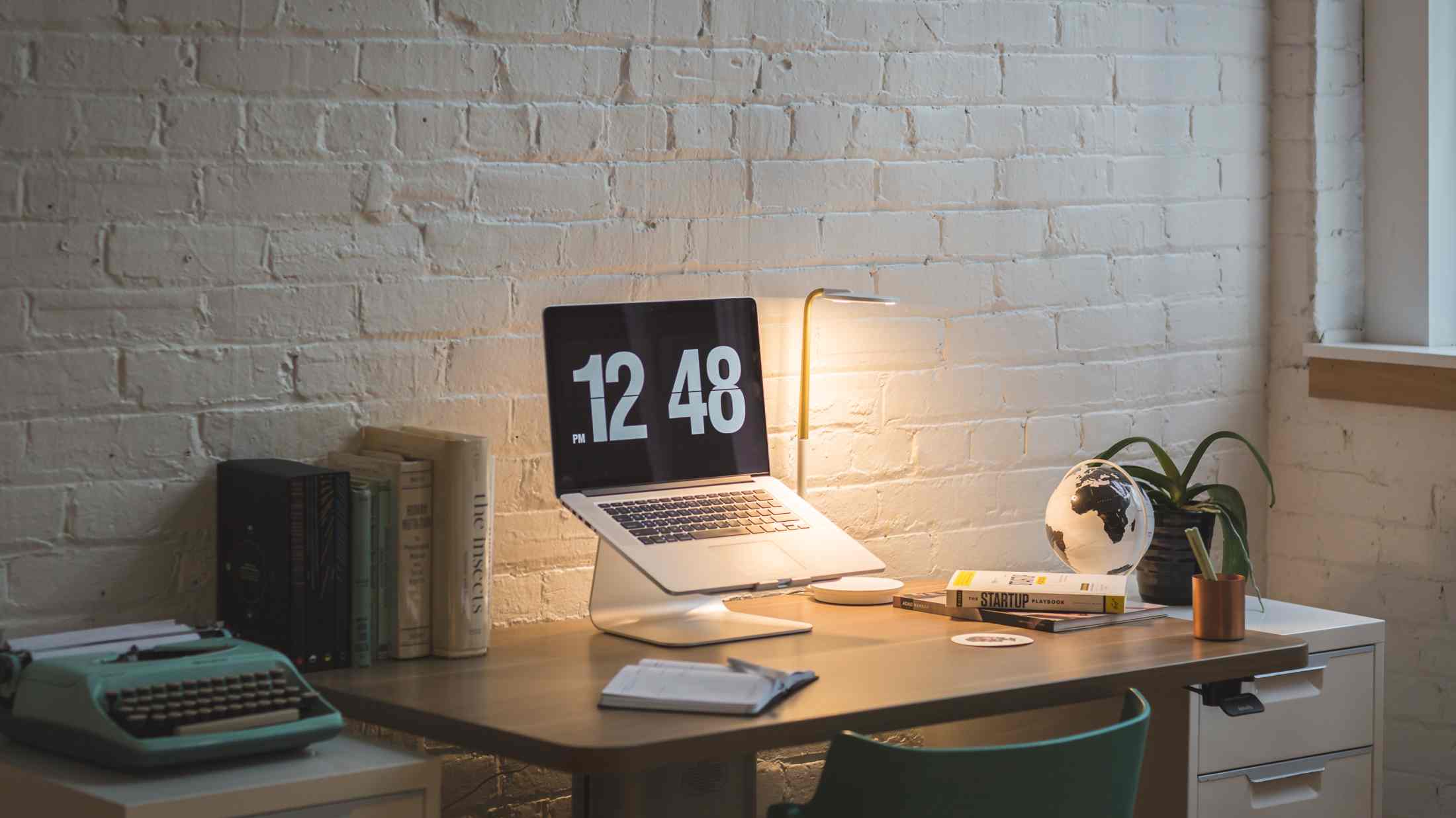 Macbook on desk beside table lamp