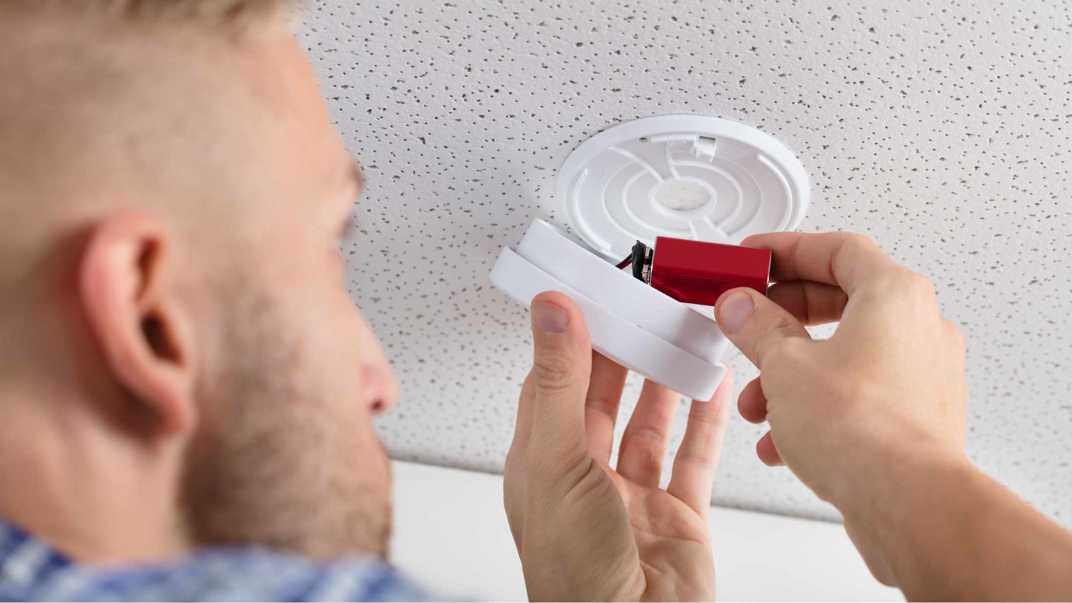 Man changing battery in fire alarm