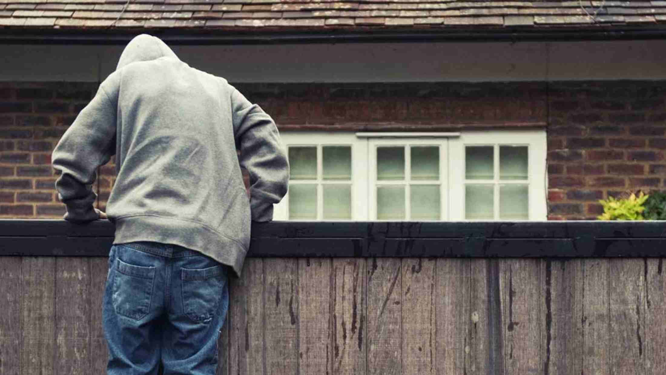 A thief climbing over a wooden fence