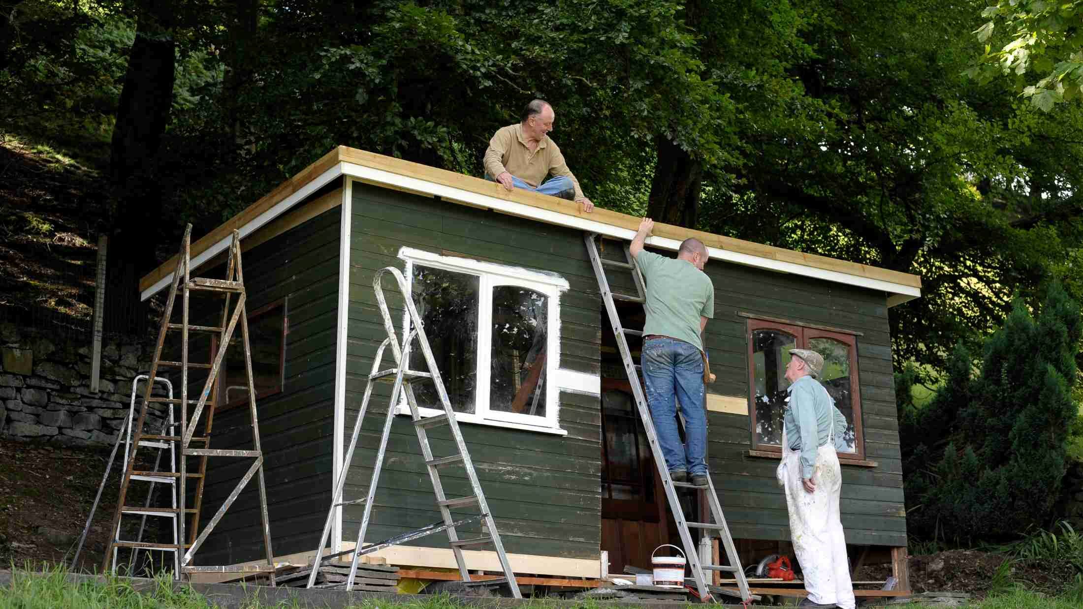 Men working on a garden shed structure in a garden