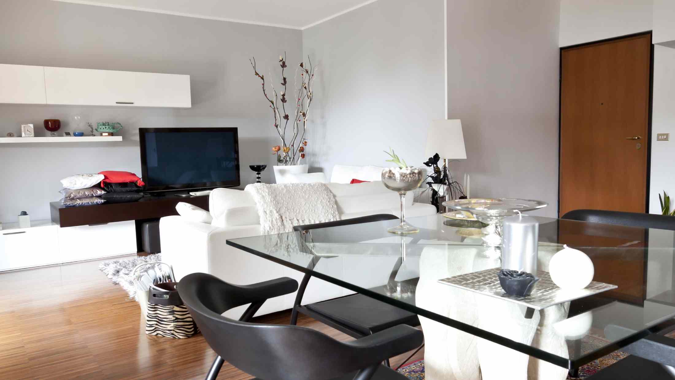 Modern living room with glass table, white sofa and television