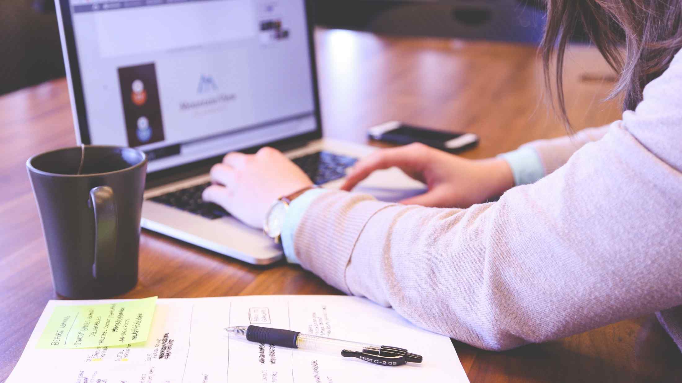 Woman making planning notes on macbook