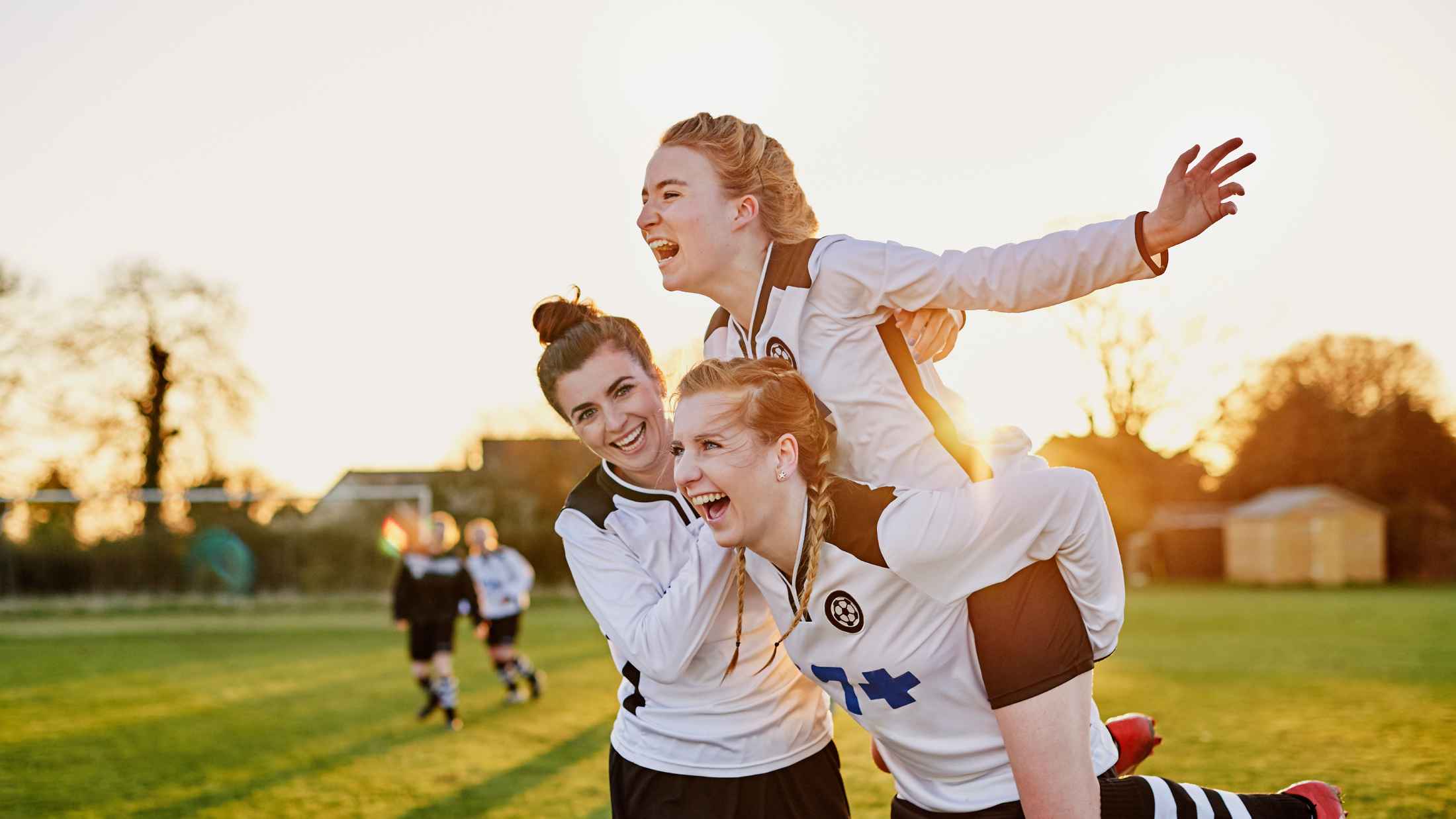 Young female footballers celebrating a goal in evening light