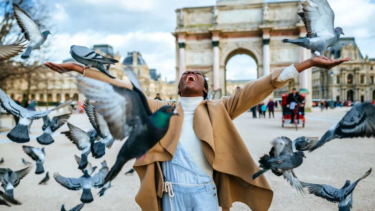Black woman stood in front of the Arc de Triomphe with her arms outstretched