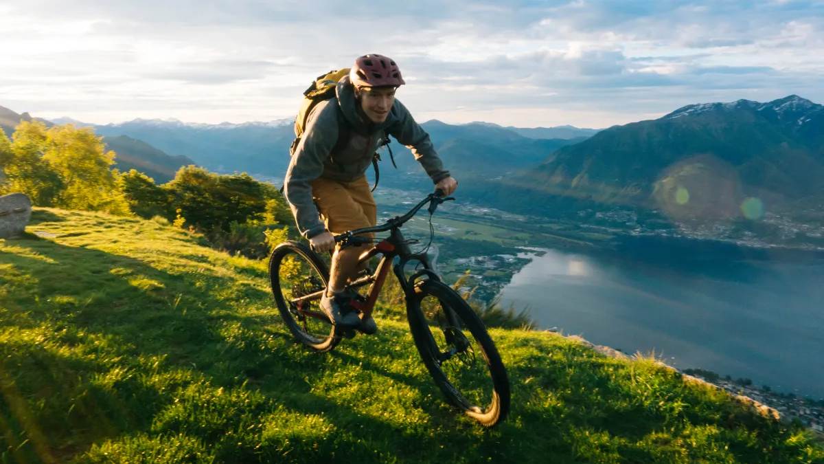 Man mountain biking on the top of a mountain overlooking a lake